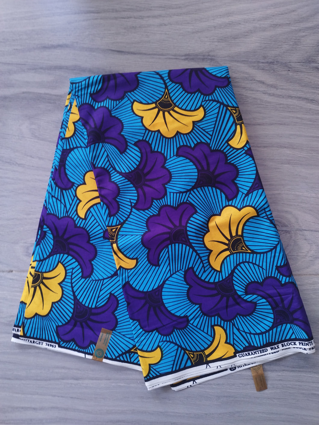 Tissu wax - fleurs de mariage violettes et jaunes fond bleu - par 50 centimètres